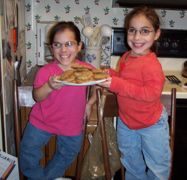 2 girls holding a plate of cookies they just made